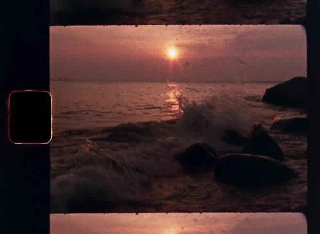 Waves crashing on rocks as the sets on the horizon over the ocean