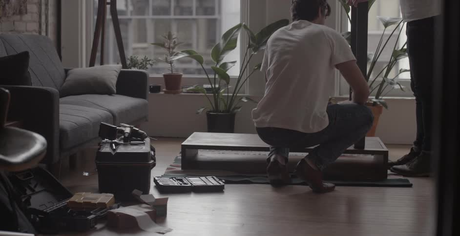 Men assemble a piece of furniture on  floor