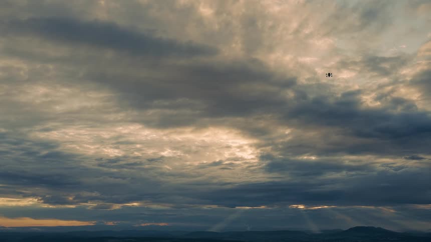 A drone flying high into the sky on a cloudy day