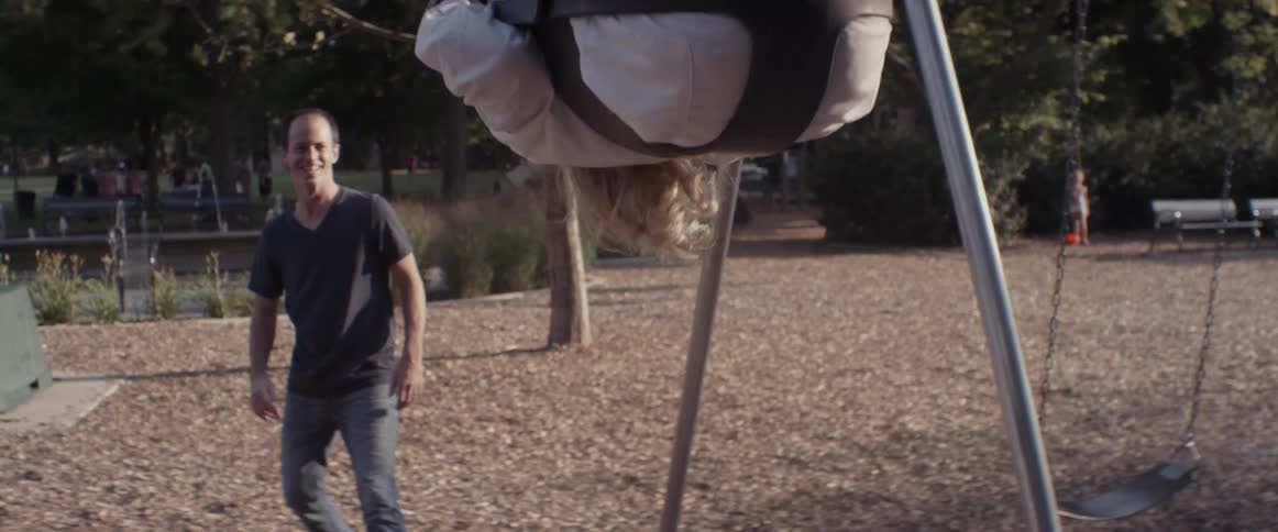 A man is pushing a child on a swing