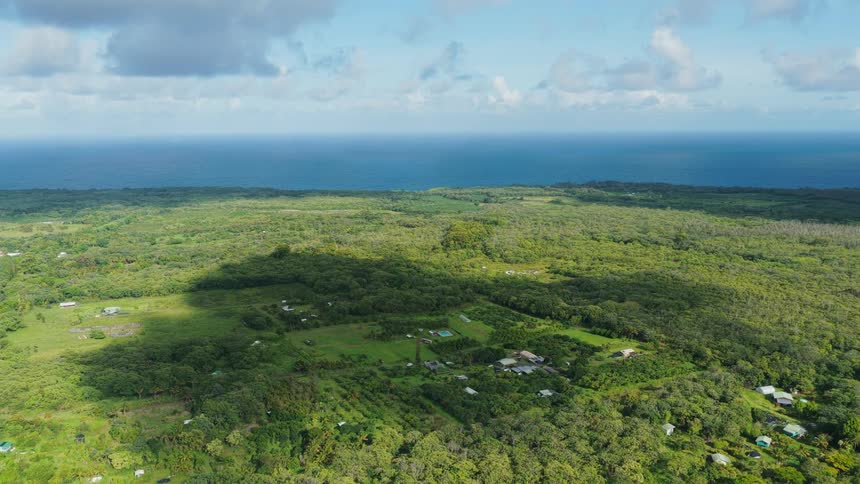 Vast green landscape stretches to the sea under a partly cloudy sky