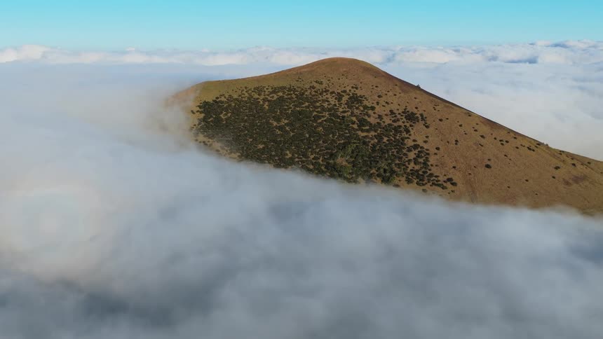 A mountain rises above the clouds