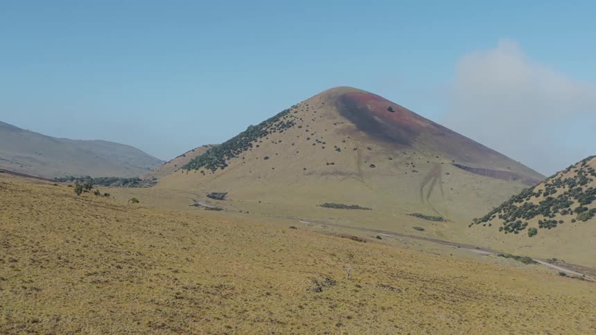 Dormant volcano shows dark marks on its slope under a blue sky
