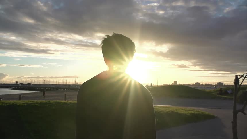 A man walks near a beach at dusk