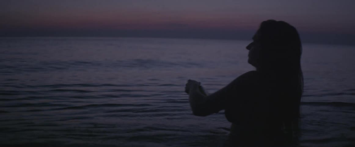A woman wades into the water at dawn