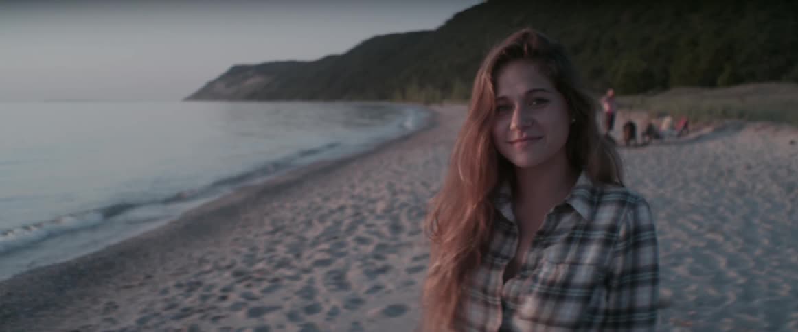 A woman looks up and smiles on the beach