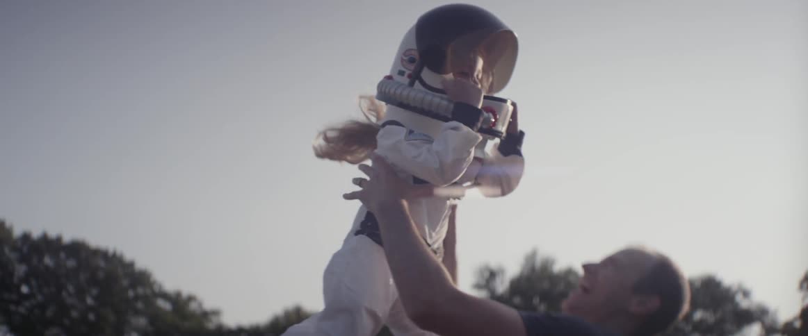 A man throws a girl wearing a space suit into the air