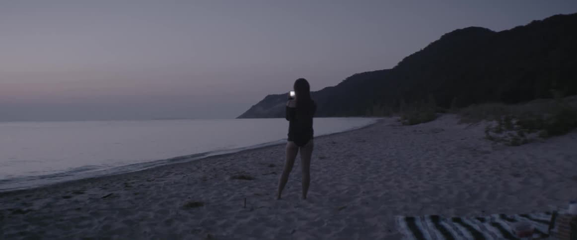 A woman takes a photograph on a beach