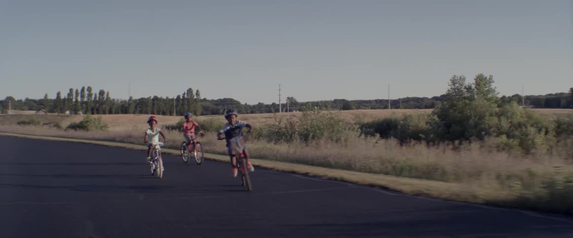 Three children ride bicycles on a road