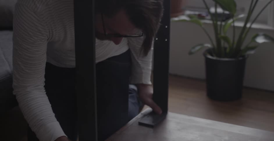 A man assembles a piece of furniture on the living room floor