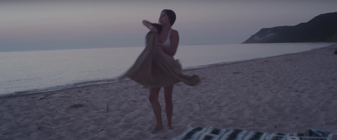 A woman runs out of the ocean onto a sandy beach