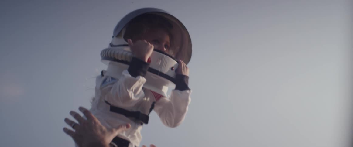 A man throws a girl in an astronaut costume into the air