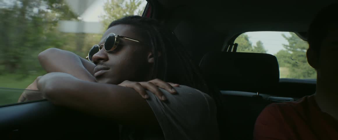 A man leans out of a window riding in a car