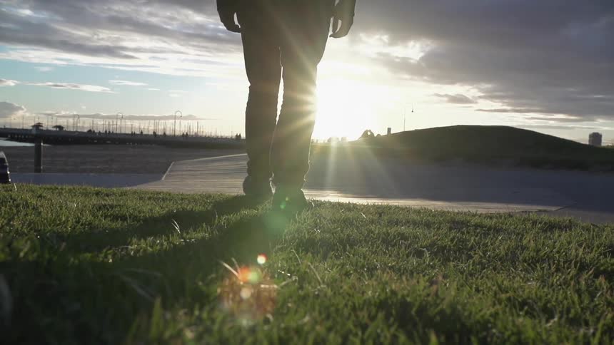 Man walks on the grass by the shore on a cloudy day