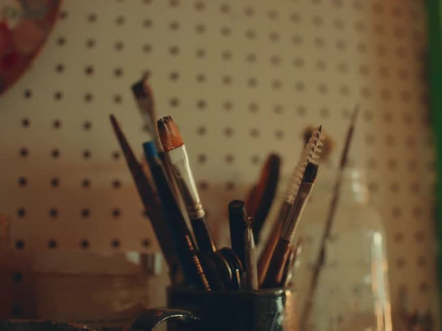 The mug is full of painting supplies and brushes