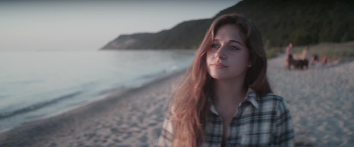 A woman smiles and laughs on a beach