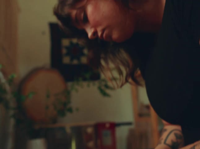 A tattooed artisan skillfully shapes a clay pot on a spinning wheel in a cozy earthtoned studio