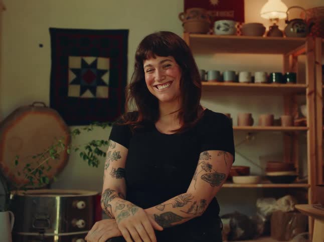 Portrait of a young woman seated in a pottery studio during daytime