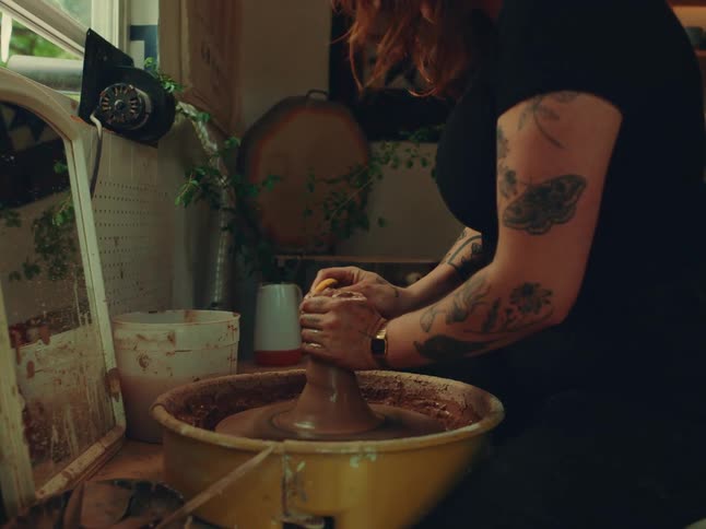 Woman working with clay on a manual machine