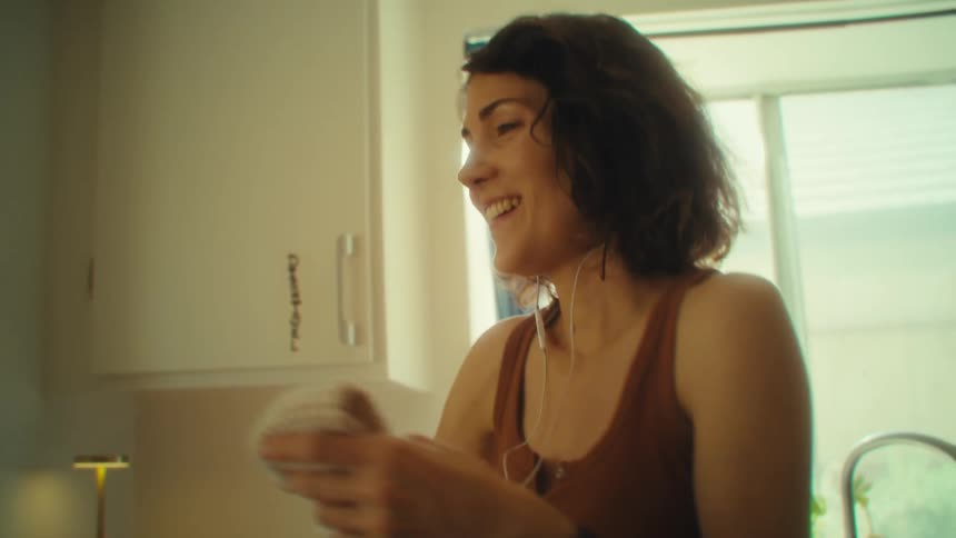 Woman smiles in the kitchen while holding glass cups