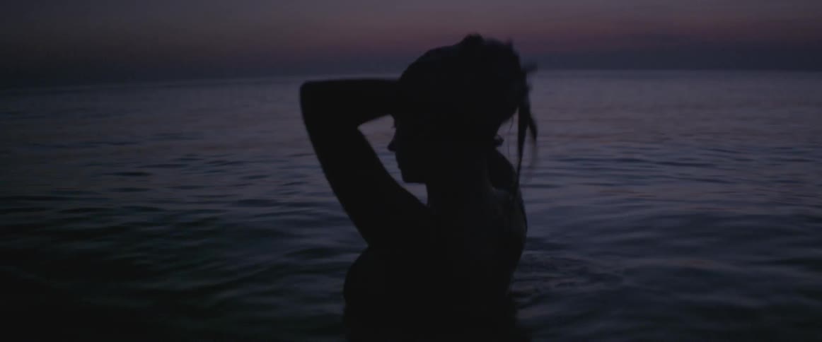 A woman washes her hair in the ocean water