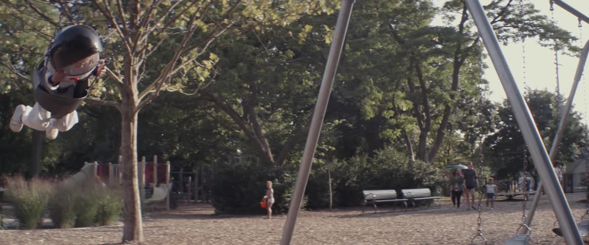 A child wearing a space costume swings in a park