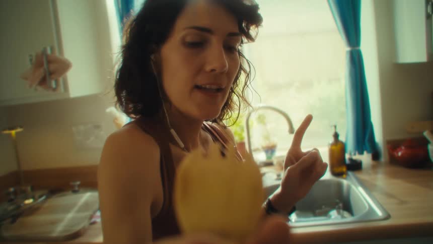 Woman sings holding a wooden spoon as if it were a microphone