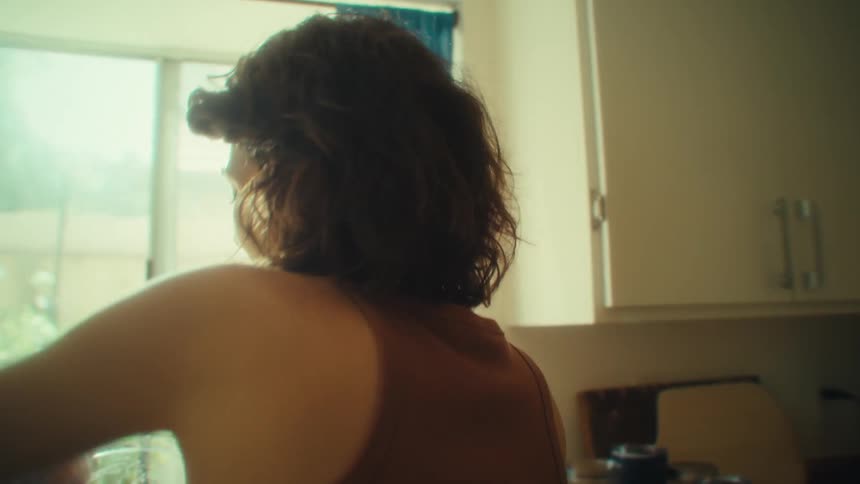 A woman happily does chores in the kitchen while listening to music