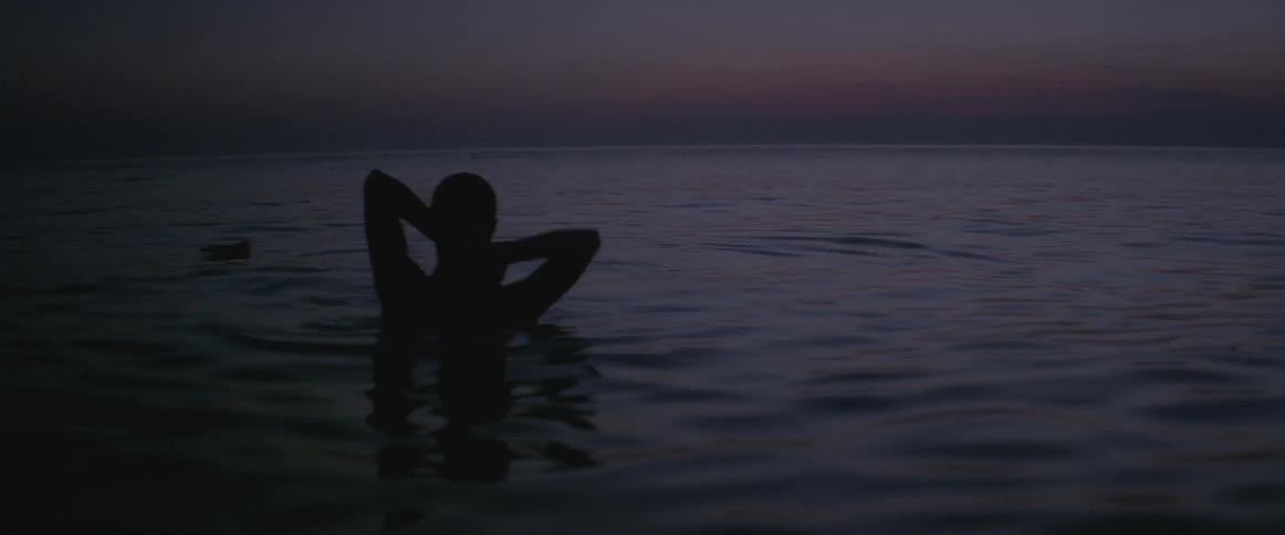 A woman jumps out from under the water at dawn