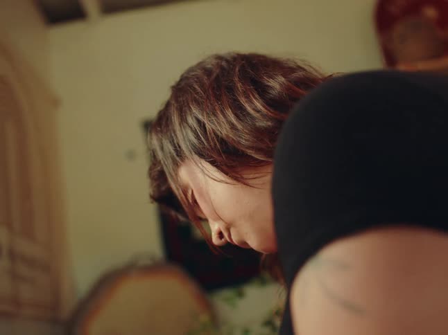Brownhaired woman with bangs looks downward in an indoor setting