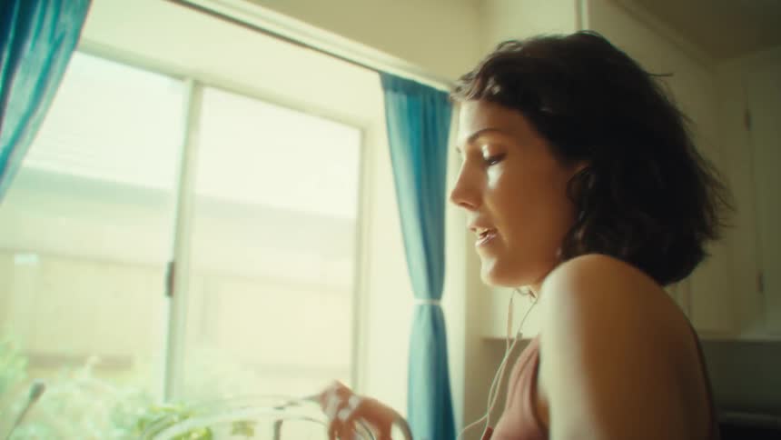 Woman sings cheerfully in the kitchen wearing earphones