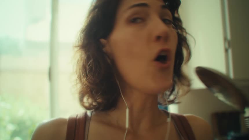 Woman sings in the kitchen holding a ladle as a microphone