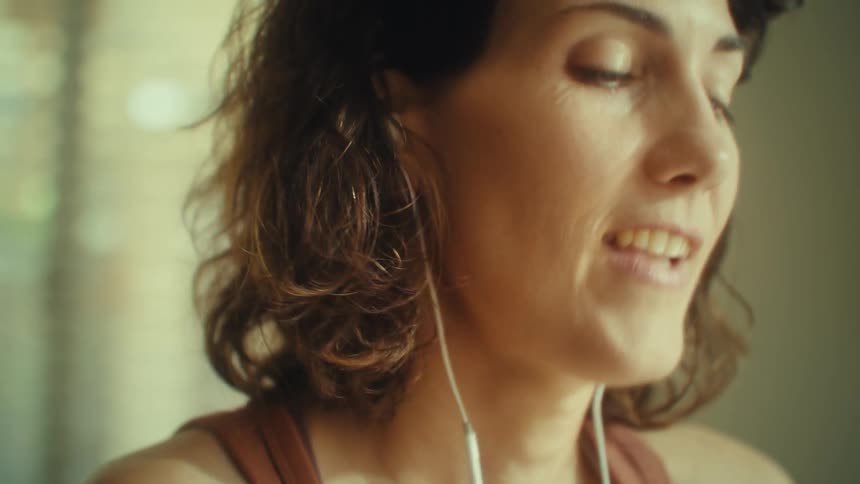 Woman smiles wearing earphones while looking outside
