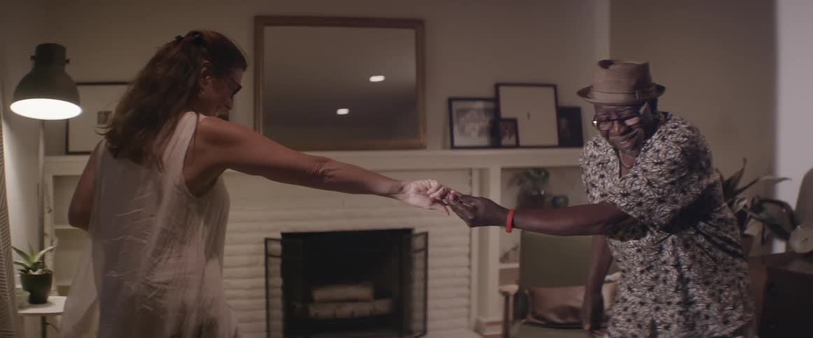 A man and woman smile and dance at home