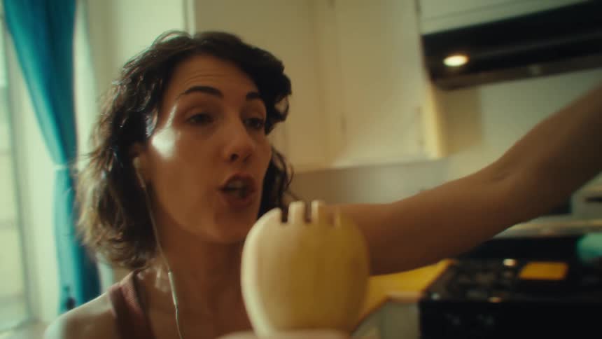 Woman sings enthusiastically using a wooden utensil as a microphone