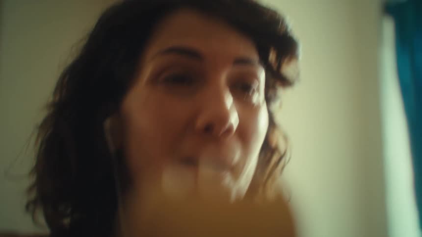 Woman smiles and sings cheerfully holding a wooden utensil as a microphone
