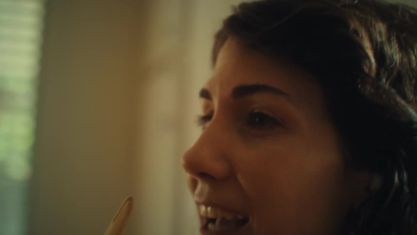 Woman sings and dances in the kitchen using a wooden spoon as a microphone