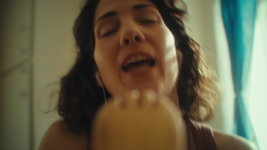 Woman sings with closed eyes using a wooden utensil as a microphone