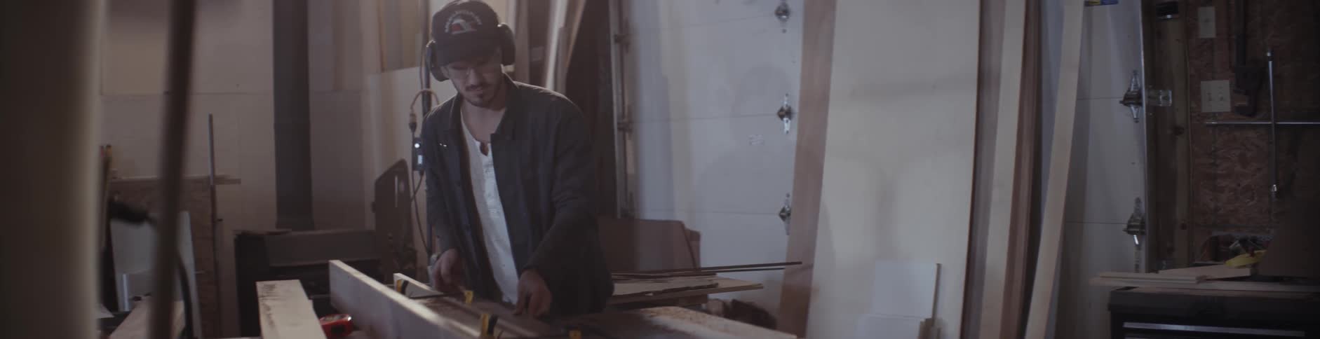 A man pushes a piece of wood into place on a table