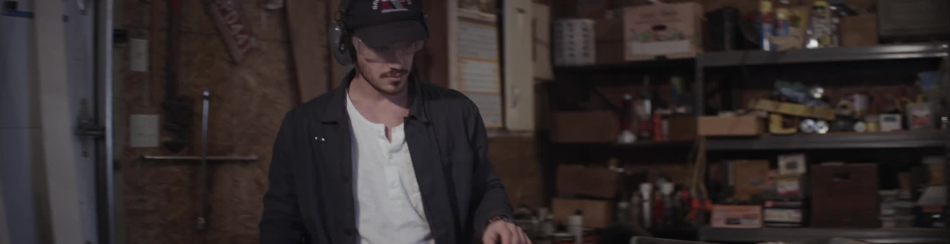 A man wearing ear protection turns on a machine