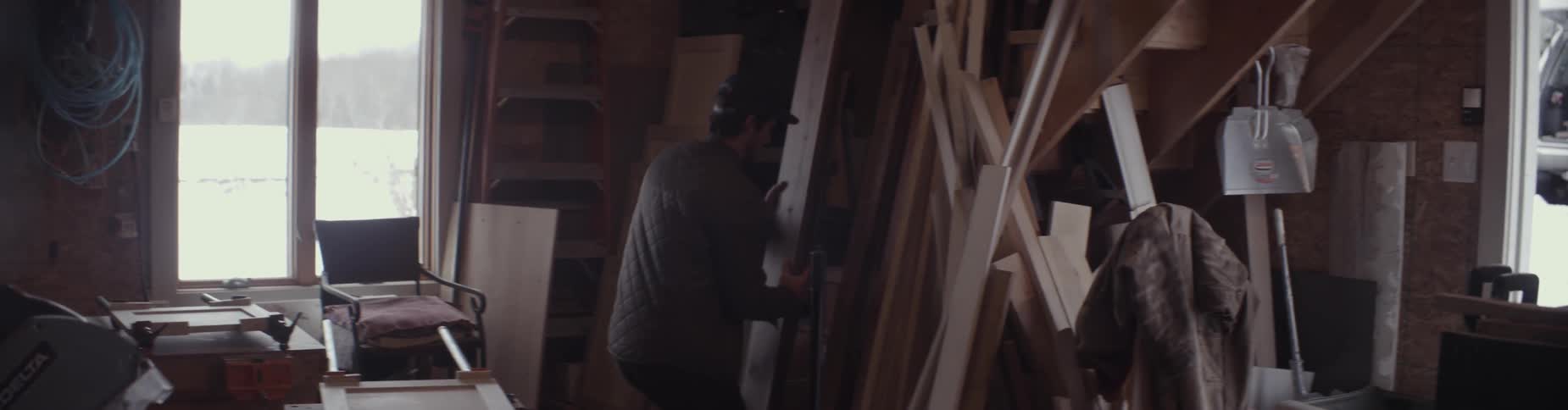 A many carries lumber in a workshop