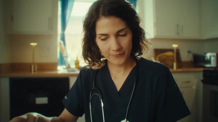 Close up of a female medical professional going through documents while sitting at a table in a kitchen during daytime