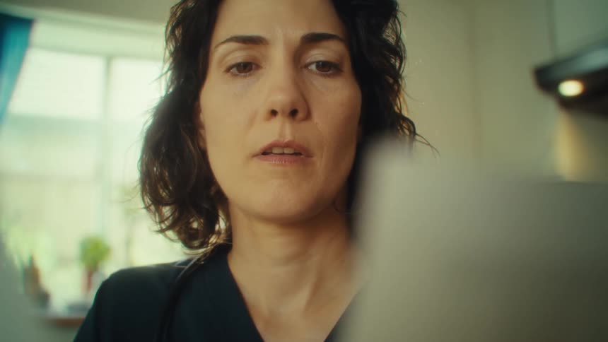 A woman with short brown hair looks down at documents with a look of realization and a smile in her face