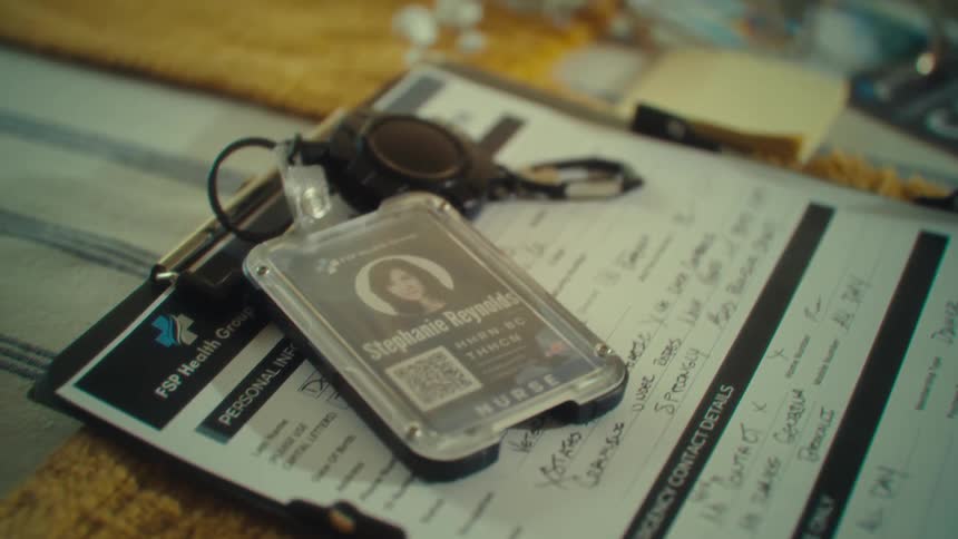 Nurse badge on top of a clipboard with completed forms