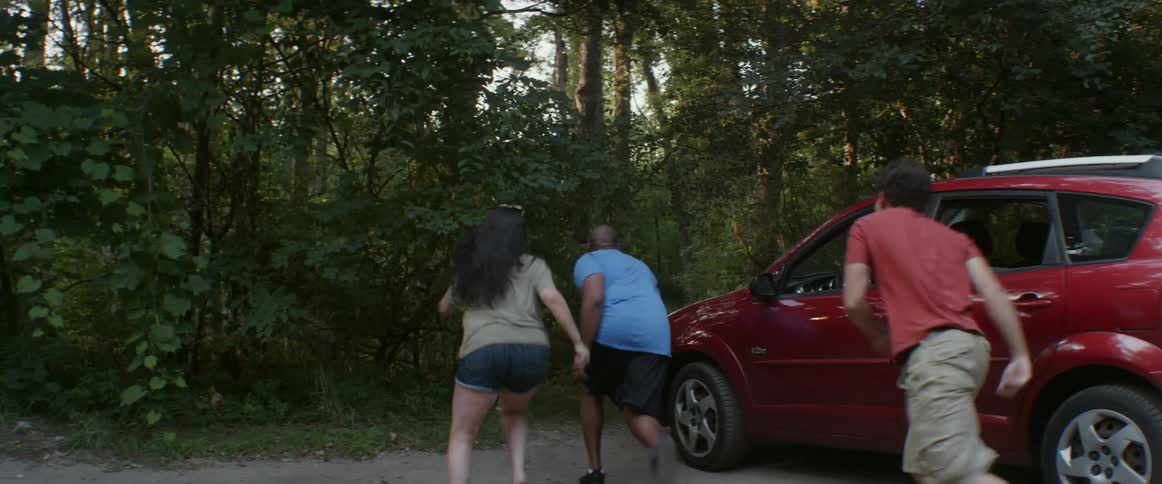 People get out of a car and run in the woods