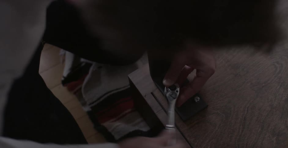 A man is using a wrench to screw in a table leg