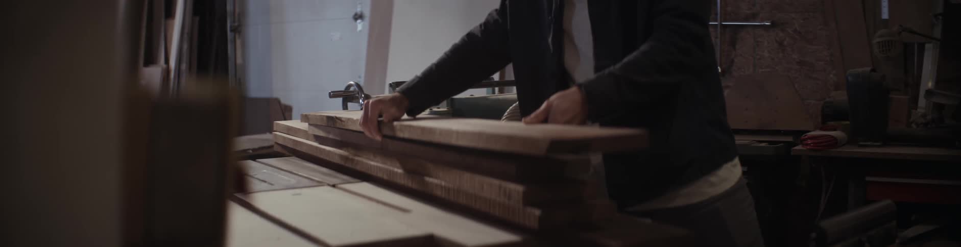 A man adjusts a piece of wood on a table