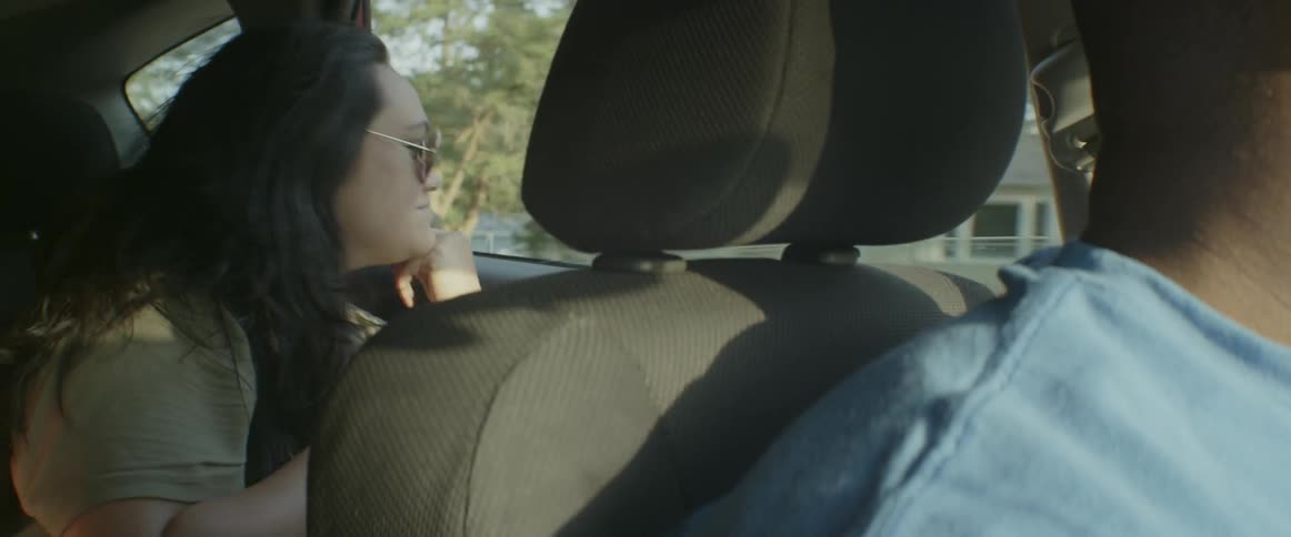 A woman sits in back of a car moving around