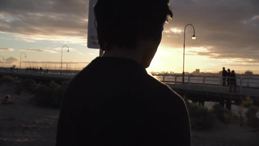 Man walking at sunset towards a boardwalk