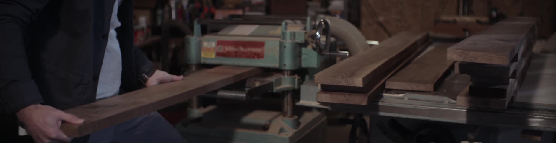 A man examines a piece of lumber before feeding it through machinery